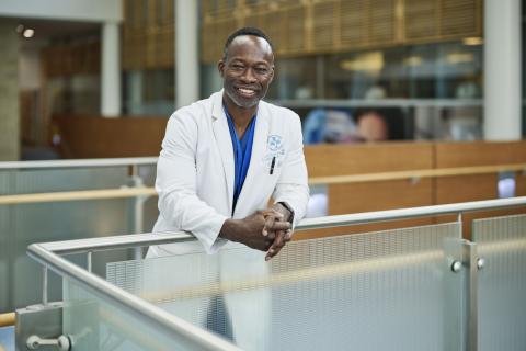 Dr. Kwadwo Kyeremanteng standing at a railing hands casually clasp smiling at you
